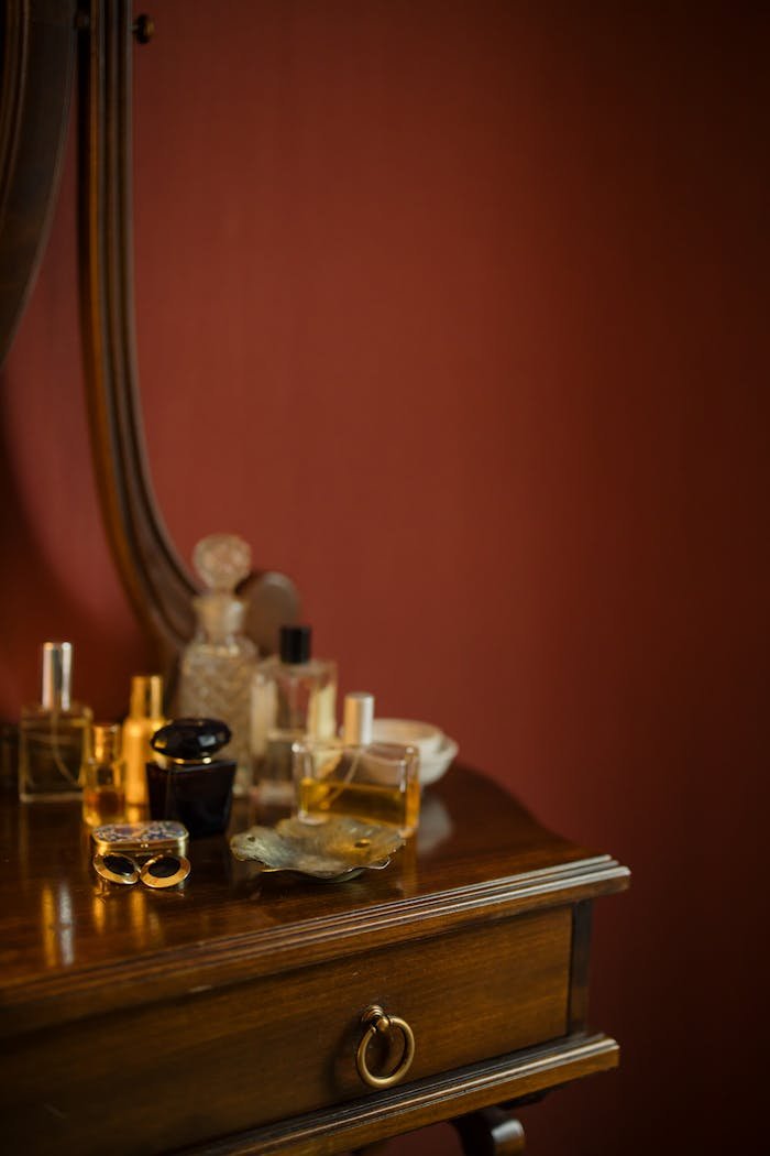 Elegant collection of vintage perfume bottles displayed on a wooden dresser with a classic mirror backdrop.